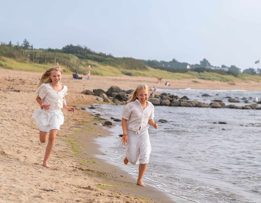 Barn som leker och springer på barnvänlig sandstrand vid havet i Ängelholm nära Destination Råbocka